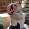 Une tête de mannequin présente le Bandeau Le P'tit Vaness', un bandeau à motifs orange et noir