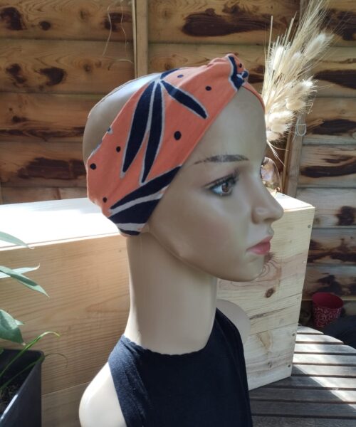 Une tête de mannequin présente le Bandeau Le P'tit Vaness', un bandeau à motifs orange et noir