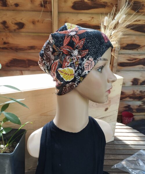 Un mannequin aux traits réalistes porte le Bonnet Catherine (sans bandeau), un foulard coloré orné de motifs floraux et papillons.